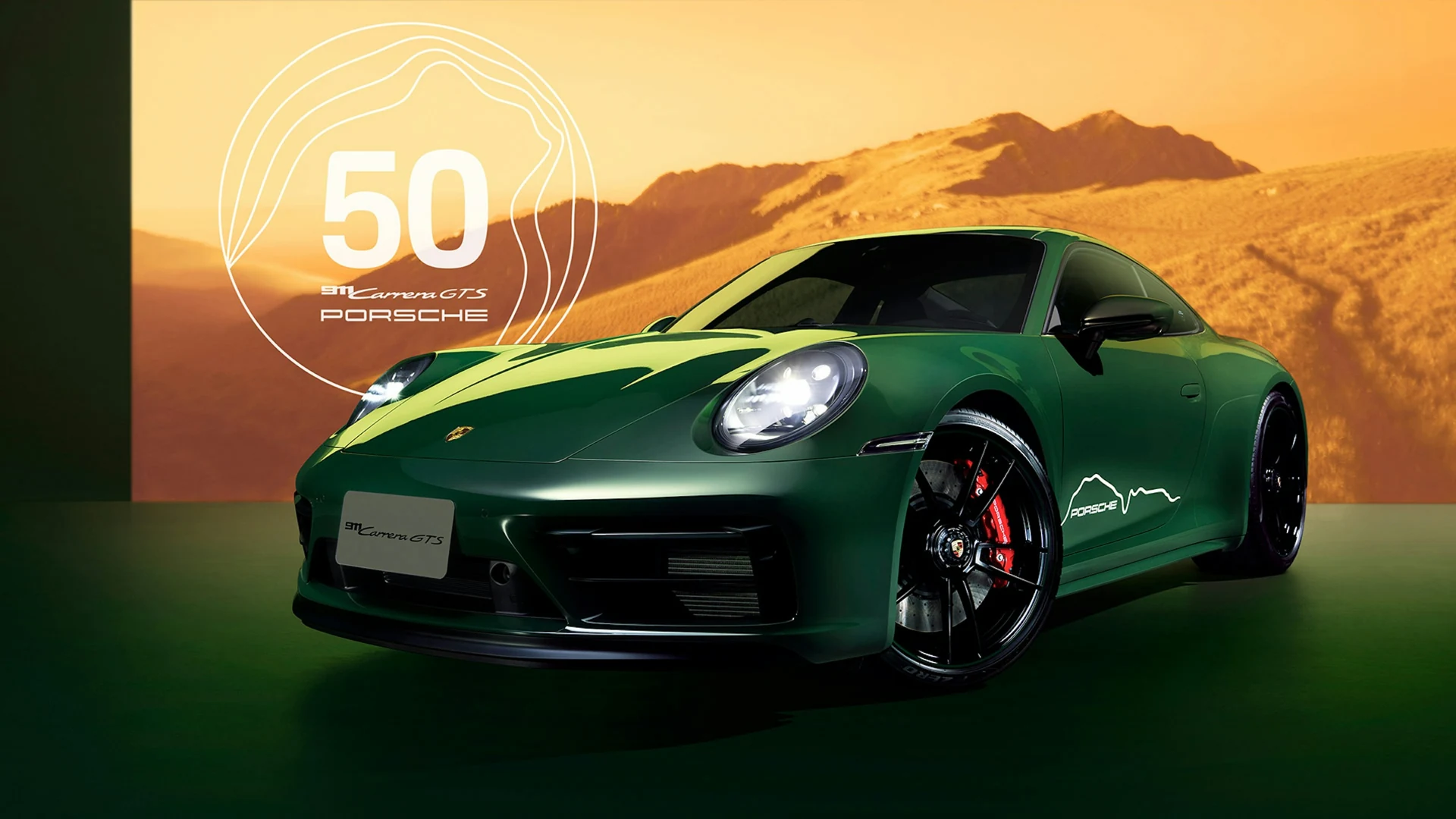 Front three-quarter view of the anniversary Porsche against golden mountains